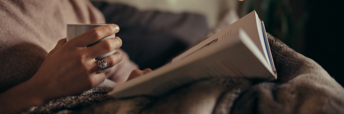 Woman drinking decaffeinated coffee whilst reading a book at bedtime