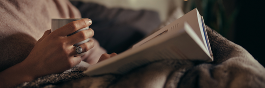Woman drinking decaffeinated coffee whilst reading a book at bedtime